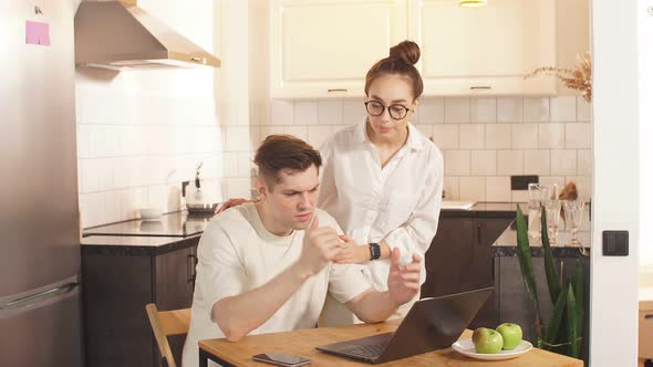 Man Work From Home, His Careful Wife Next To Him.