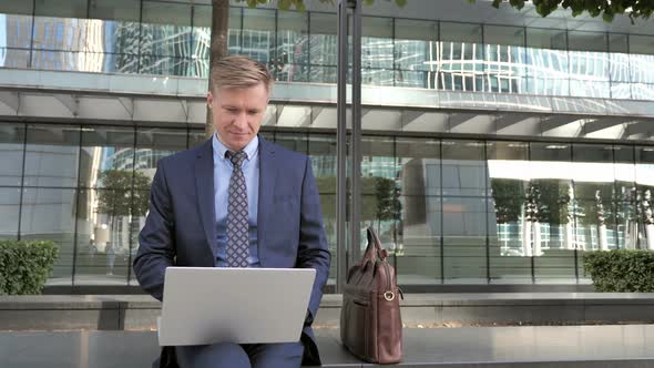 Businessman Working on Laptop Outside Office