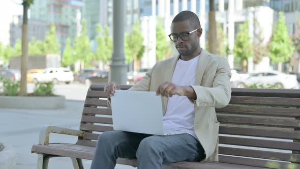 African Man Leaving Bench After Closing Laptop