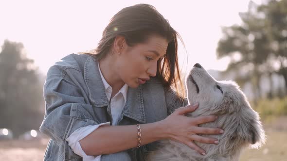 Pretty Girl Is Walking with a Cute Fluffy Dog in the Field