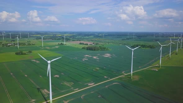 Aerial view of wind turbines generating renewable energy in the wind farm, sunny summer day, lush gr