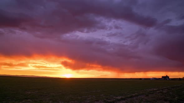 Colorful sunset timelapse with farmhouse over the flat plains