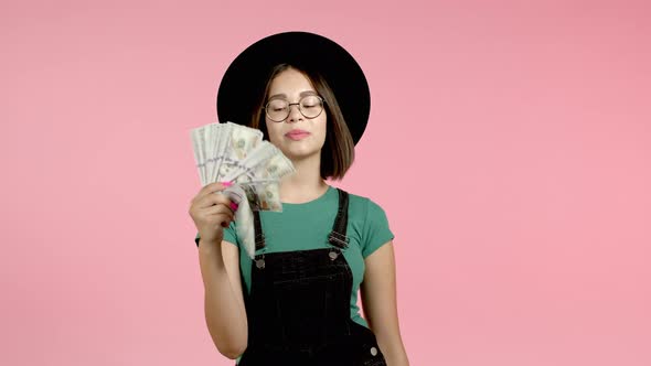 Amazed Excited Hipster Woman Showing Money - U.S. Currency Dollars Banknotes on Pink Wall. Symbol of