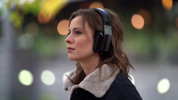 Close-up Portrait of a Young Woman Listening To Music with Headphones in the Open Air. It Stands on