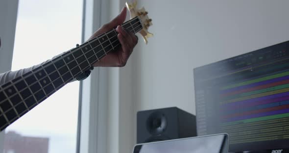 Close Up Angled Up of a Young Man Playing a Bass Guitar in a Home Music Studio