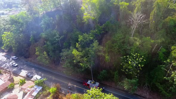 Aerial view of a firetruck spraying water on a smoking wildfire - Static, drone shot