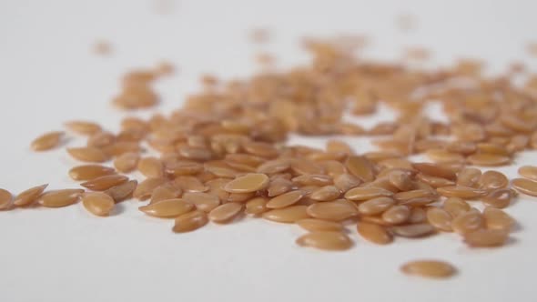 Flax seeds fall in a heap on a white kitchen table 