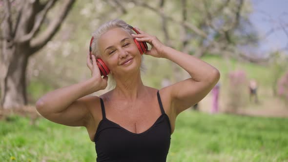 Joyful Smiling Retiree Holding Headphones with Hands Dancing to Music in Slow Motion