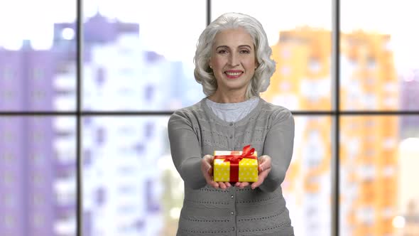 Old Woman Giving Gift Box with Both Hands