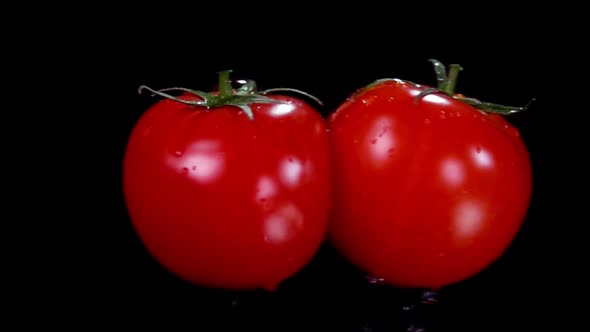 Two Ripe Red Tomatoes Are Flying Towards Each Other on the Black Background