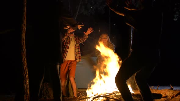 Joyful People Dancing Around Fire in Woods at Night, Party With Friends, Ritual