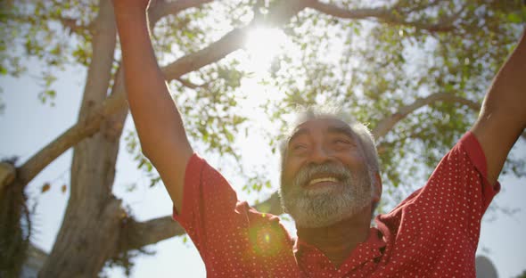 Low angle view of active African American senior man performing yoga in the garden of nursing home 4