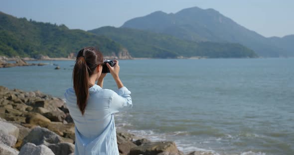 Woman take photo on cellphone at seaside