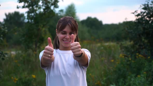 Young Nice Girl in Nature in White T-shirt Shows Thumbs Up Gesture in Slow Motion