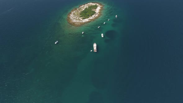 Aerial view of boats moored near a tiny island in Adriatic Sea