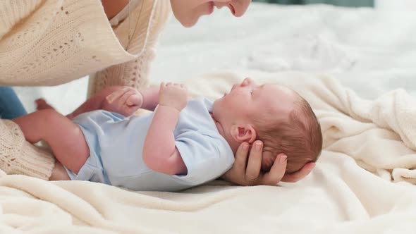 Slow Motion of Young Caring Mother Putting Her Little Baby Son on Soft Blanket in Bedroom