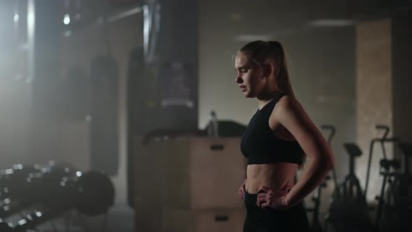 Medium Portrait of Exhausted Athletic Woman in Black Sportswear Breathing Hard and Resting