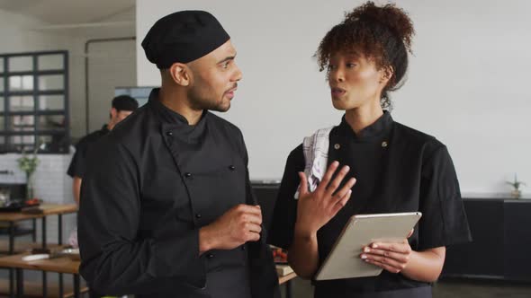 Mixed race male and female chefs using digital tablet