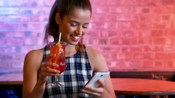 Happy woman taking selfie on mobile phone while having cocktail