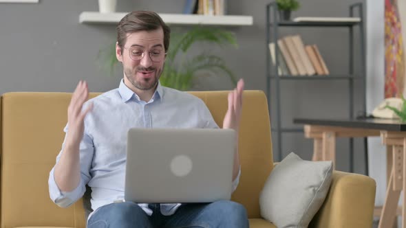 Young Man Doing Video Call on Laptop on Sofa