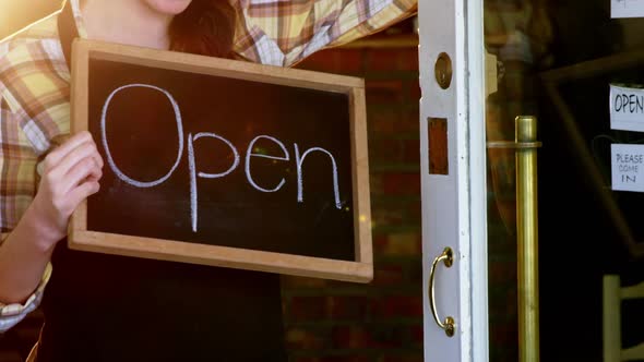 Waitress showing chalkboard with open sign