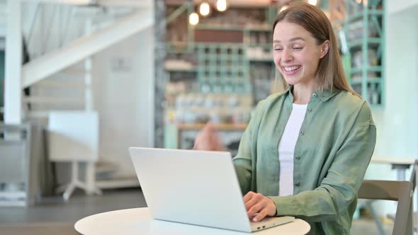 Excited Woman Celebrating Success on Laptop in Cafe