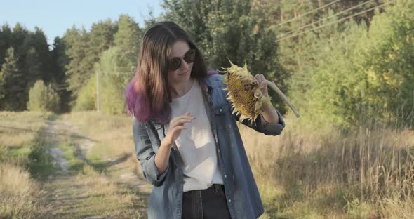 Young Beautiful Girl with Ripe Sunflower in Hands