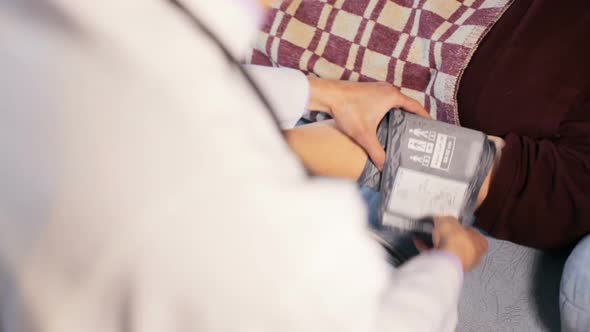 The doctor checks the blood pressure of an elderly patient at home.
