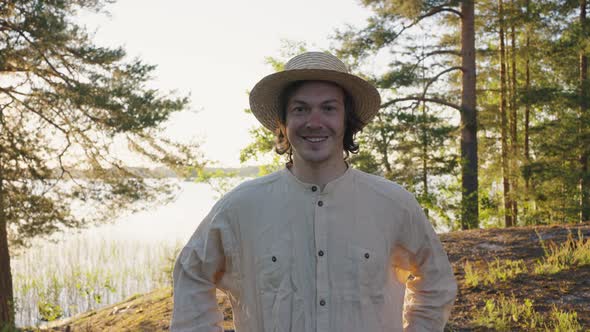 Young Man in Straw Hat Smiles Looking Straight on River Bank