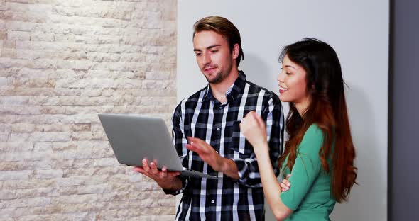 Male and female executives discussing over laptop