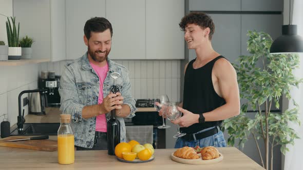 LGBT Male Couple in Love Preparing a Romantic Dinner and One of the Partners Opens the Wine While