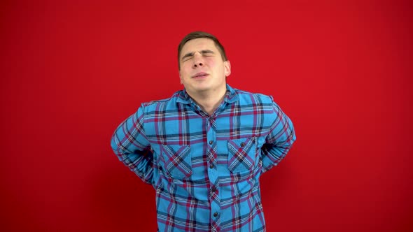 A Young Man Has a Backache and Is Holding It in His Hands