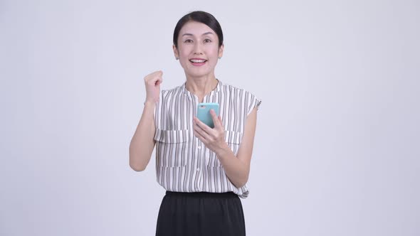 Happy Beautiful Asian Businesswoman Using Phone and Getting Good News