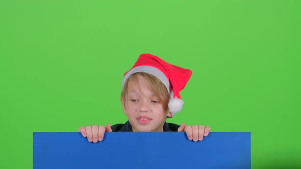 Teen in Cap Emerges From Behind the Board on a Green Screen