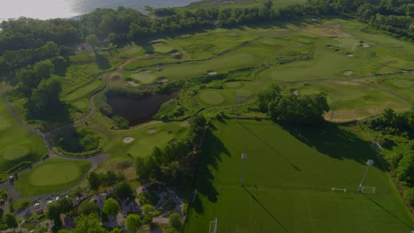 Backwards Aerial Pan of a Golf Course by the Water on a Sunny Day