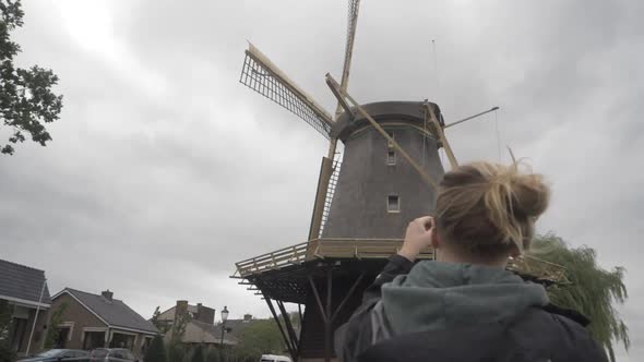 Panning Shot of a Young Woman Taking a Picture of an Old Dutch Windmill
