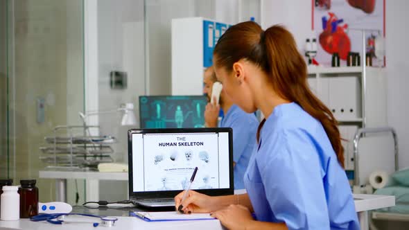 Doctor Assistant Analyzing Digital Human Skeleton on Laptop