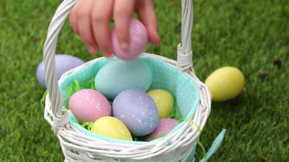 Close-up shot little girl putting Easter eggs into basket