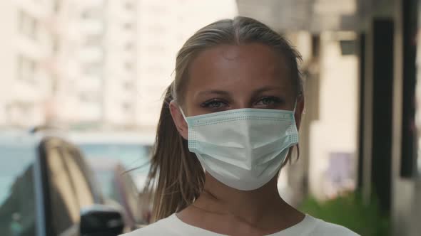 A Woman in a Hot Country is Standing in a Mask on the Street