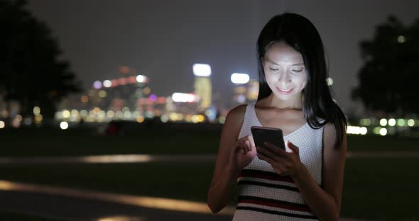 Woman looking at mobile phone in the city at night 