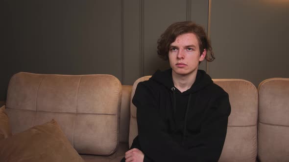 Scared Young Man Watches Horror Film on Couch at Home