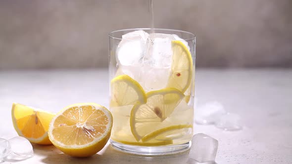 Pour homemade lemonade with lemon slices and ice into a glass.