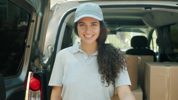 Slow Motion Portrait of Young Woman Courier Standing Near Van Full of Parcels