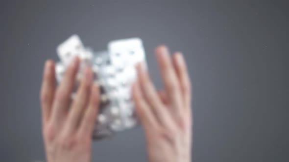 Caucasian Hands Throw Silver Blisters with Various Pills in Slow Motion