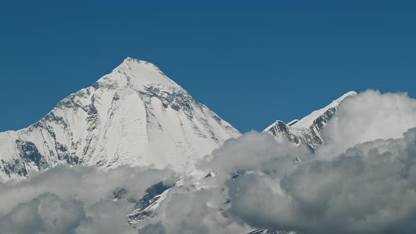 Timelapse Clouds Swirl Over a Mountain Valley a Snowy Peak in the Distance