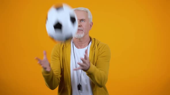 Experienced Aged Sport Coach Catching Football on Orange Background, Profession