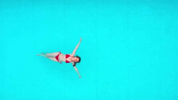View From the Top As a Woman in Red Swimsuit Lying on Her Back in the Pool