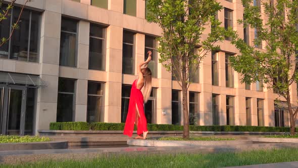 Beautiful Young Girl Dancing on the Street of a Modern City and Is Reflected in the Water. She Is