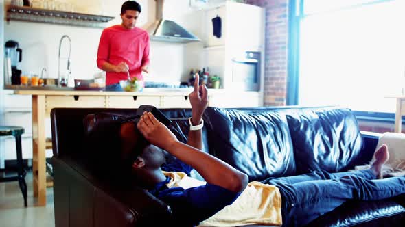 Man using virtual reality headset while friend preparing food