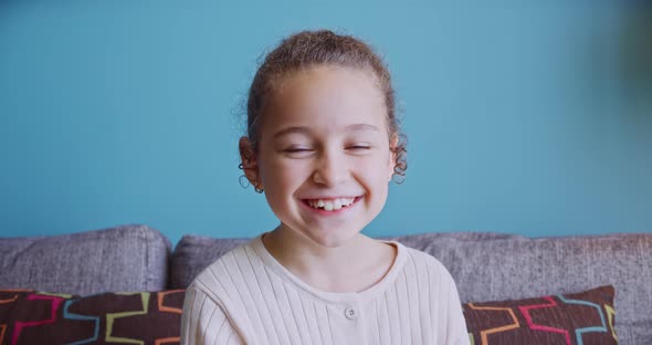 Portrait Funny Little Cute Girl Smiling Child Looking at Camera are Sitting on the Couch at Home